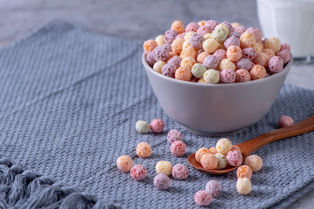 Mezcla de bolas de maíz de cereales de colores, dulces de tazón de fuente de sabor a frutas sobre fondo de cemento gris, desayuno fresco, delicioso y saludable de cerca, concepto de diseño de espacio de copia.