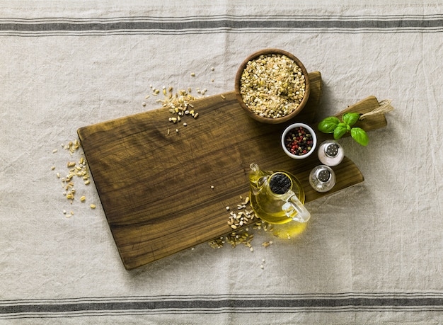 Mezcla de cereales en un tazón de madera sobre una tabla para cortar con aceite de oliva, pimientos multicolores y especias. cocina casera sobre mantel de lino