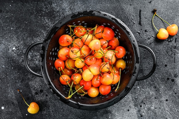 Mezcla de cerezas maduras amarillas y rojas en un colador.