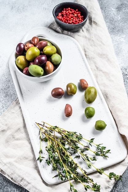 Mezcla de coloridas aceitunas saladas con un hueso. Fondo gris Vista superior