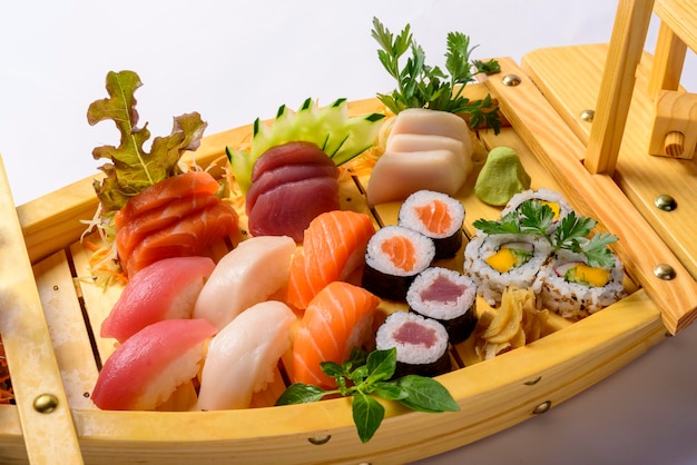 Mezcla de comida japonesa que incluye sushi y sashimi en barcaza de madera