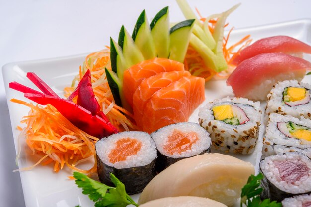 Mezcla de comida japonesa que incluye sushi y sashimi en un plato blanco