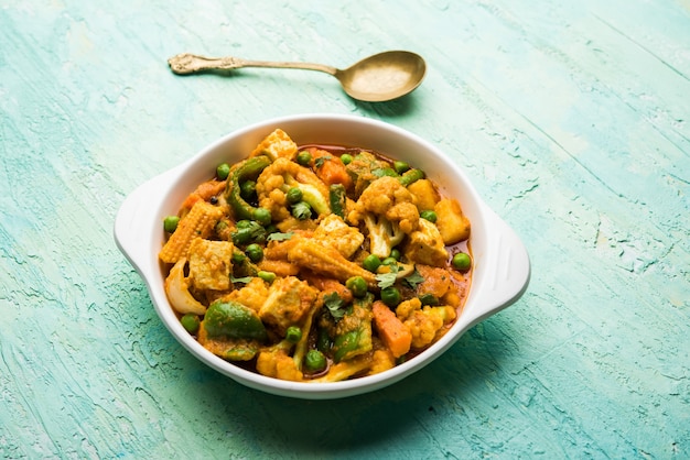 Foto mezcla de curry de verduras: la receta del plato principal indio contiene zanahorias, coliflor, guisantes y frijoles, maíz tierno, pimiento y paneer o requesón con masala tradicional y curry