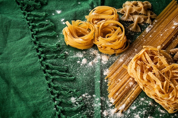 Mezcla de diferentes variedades de pasta sobre la superficie de la tela verde