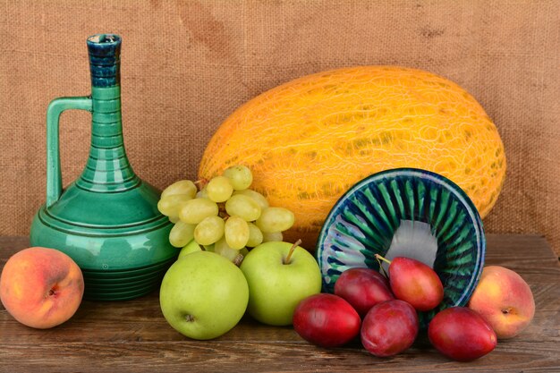 Mezcla de frutas de verano y jarra de cerámica antigua con vino