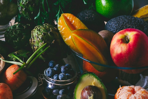 Mezcla de frutas y verduras coloridas en colores oscuros de humor en la mesa Concepto de estilo de vida saludable y plan de nutrición de dieta Ingredientes de ensalada y productos orgánicos naturales de la tienda