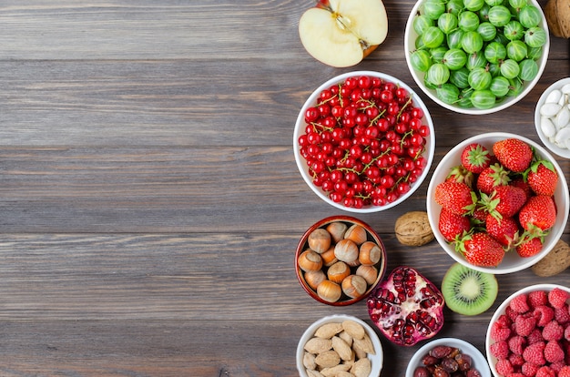 Mezcla de frutos secos, frutos secos y frutas frescas. La comida sana contiene una gran cantidad de vitaminas y oligoelementos útiles. Fondo de madera marrón. Copie el espacio.