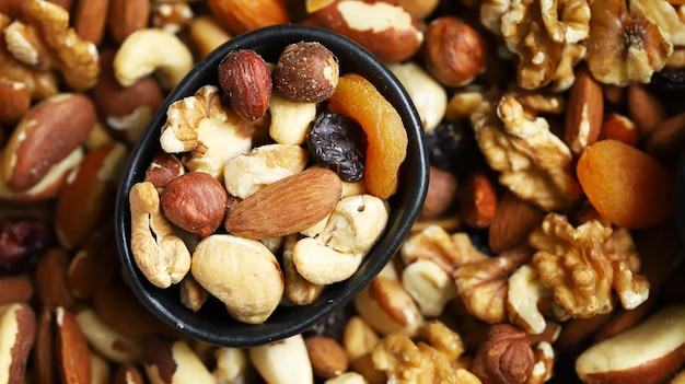 Mezcla de frutos secos y frutos secos sobre una tabla de madera y en un bol Dulces saludables