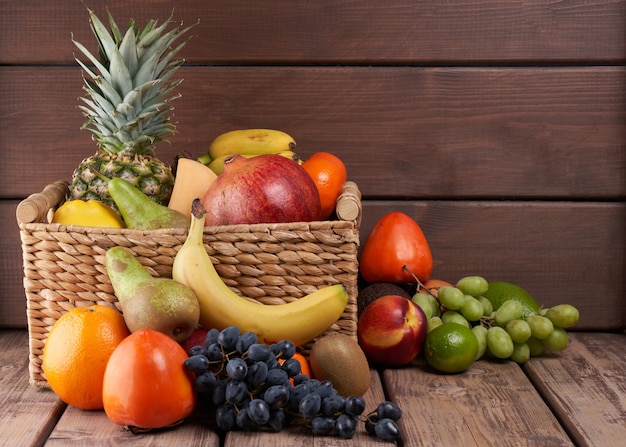 Mezcla de jugosas frutas tropicales exóticas coloridas frescas en la canasta sobre fondo de madera