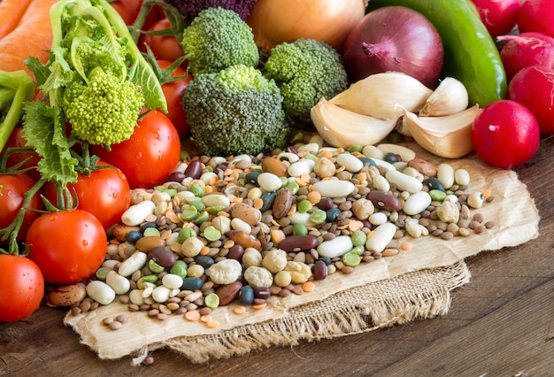 Foto mezcla de legumbres y verduras crudas en una mesa de madera marrón de cerca