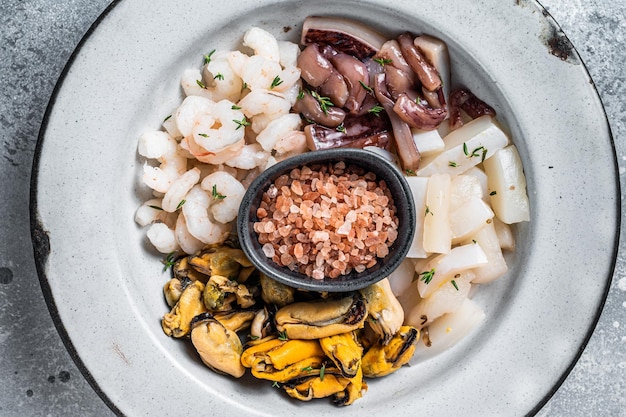 Mezcla de mariscos crudos en un plato rústico Fondo gris Vista superior