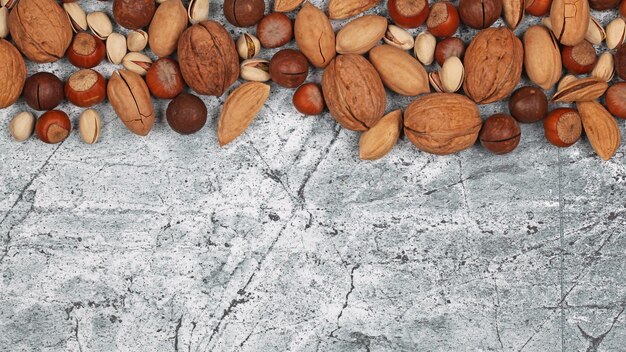 Mezcla de nueces crudas con cáscara sobre fondo de piedra gris Vista superior con espacio de copia