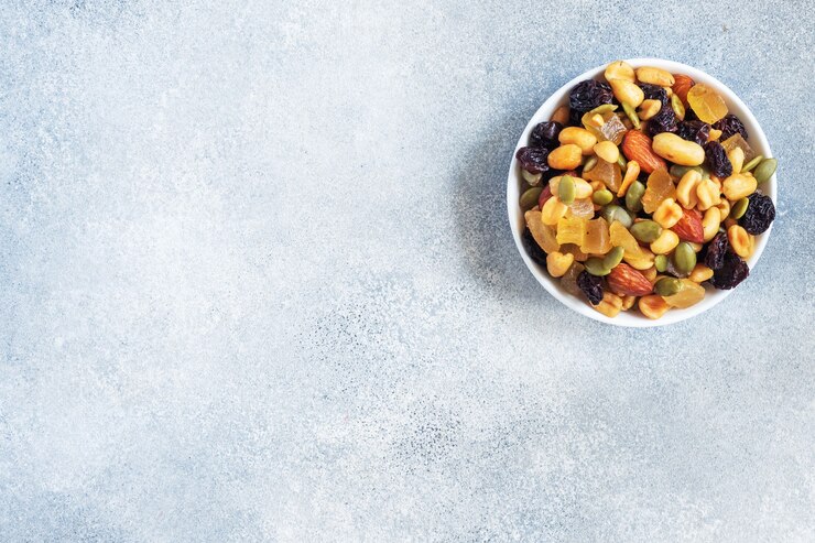 Una mezcla de nueces y frutos secos en una placa de cerámica sobre un fondo de hormigón gris. Concepto de comida sana. Copia espacio