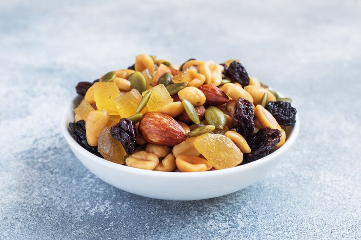 Una mezcla de nueces y frutos secos en una placa de cerámica sobre un fondo de hormigón gris. Concepto de comida sana.