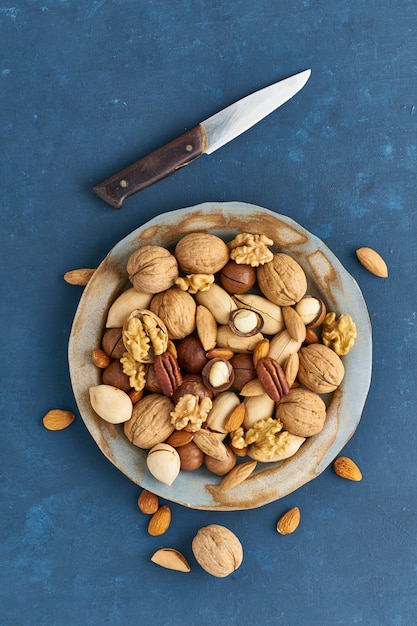 Mezcla de nueces en el plato - nuez, almendras, nueces, macadamia. Comida vegana saludable.