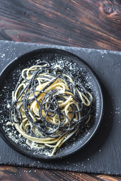 Mezcla de pasta blanca y negra con queso en el bol