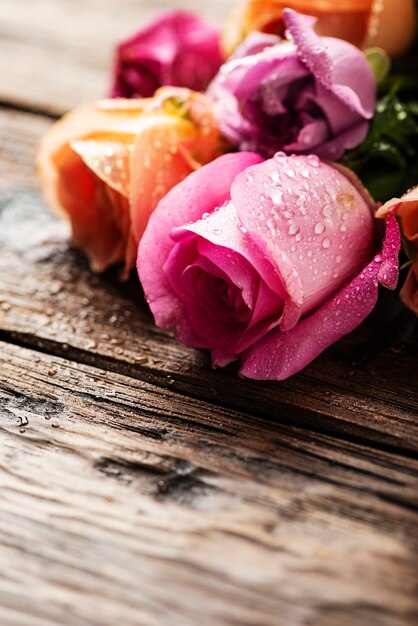 Mezcla de rosas rosadas en la mesa de madera, enfoque selectivo