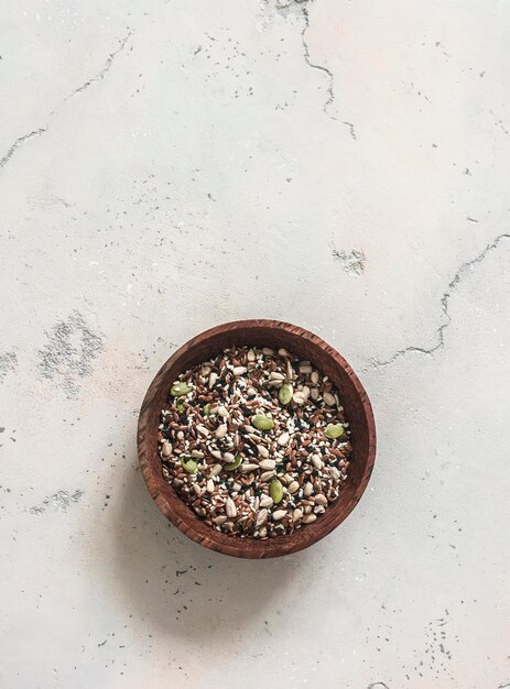 Una mezcla de semillas para batidos de ensalada sándwiches semillas de sésamo blancas negras semillas de lino semillas de calabaza semillas de girasol en un cuenco de madera sobre un fondo claro