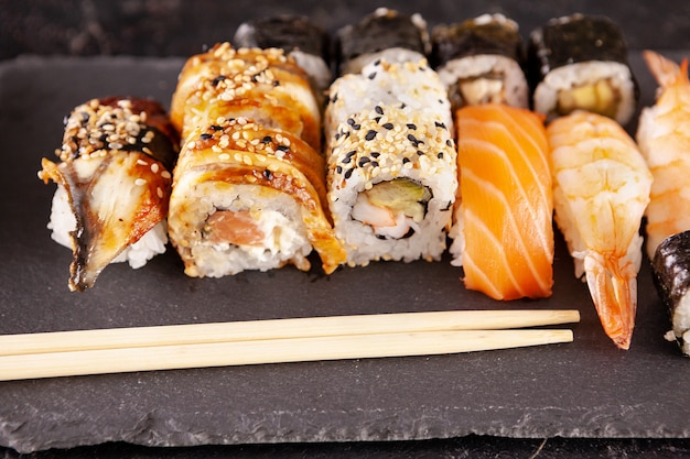 Mezcla de variedad de rollos de sushi sobre fondo negro en foto de estudio