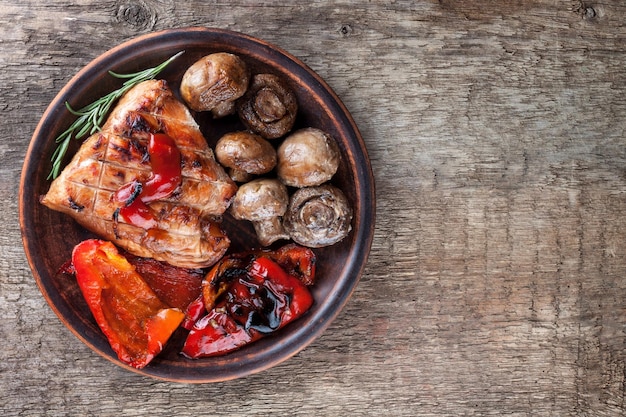 mezcla de verduras asadas y un trozo de carne en una vista superior de un plato de arcilla