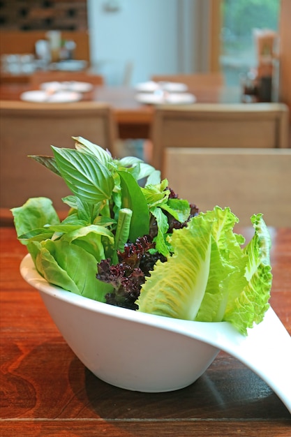 Foto mezcla de verduras frescas en un tazón blanco servido en mesa de madera