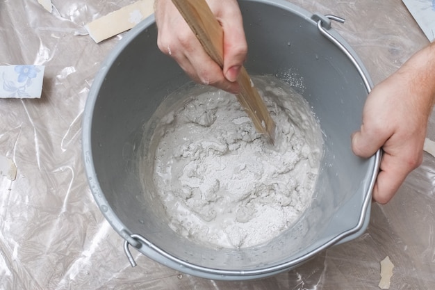 Mezcla de yeso blanco en un balde con agitador. De cerca.