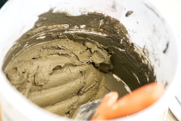 Mezclar cemento y agua en un recipiente para obtener la mezcla terminada Proceso de construcción una de las etapas de acabado Fabricación de yeso Masilla de construcción en un primer plano de balde