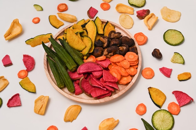 Mezclar chips de verduras con quimbombó, zanahorias, calabaza, remolacha y setas shiitake sobre fondo blanco.