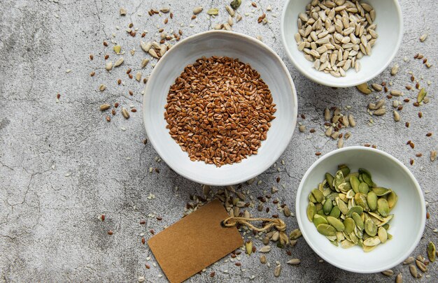 Mezcle diferentes semillas para una ensalada saludable, cuencos sobre una superficie de hormigón gris