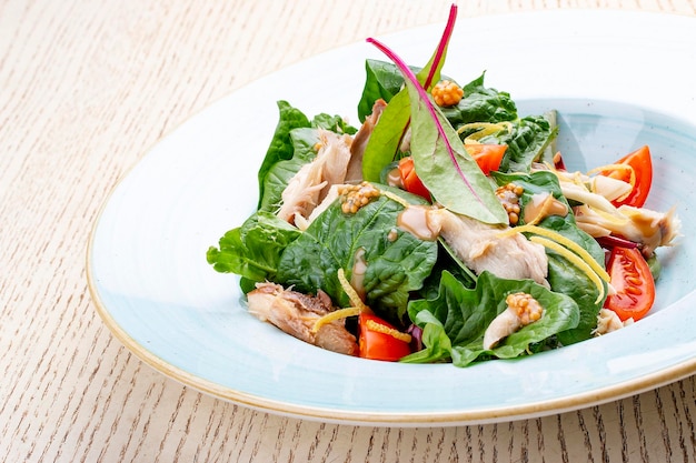 Mezcle la ensalada con pollo y tomates sobre fondo claro