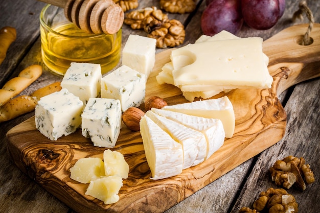Mezcle queso Emmental Camembert queso azul parmesano con nueces y miel sobre mesa de madera
