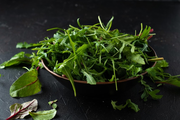 Mezcle las verduras para ensalada. Rúcula, lechuga, espinacas en tazón negro