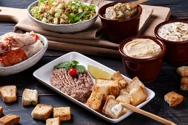 Meze é um conjunto oriental de aperitivos servidos em tigelas com babaganush, requeijão, homus e quibe