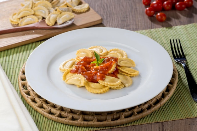 Mezzelune servido na chapa branca, com tomate cereja no fundo.