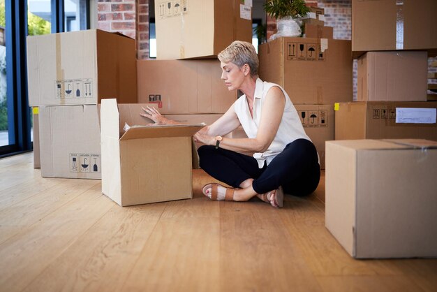 Mi casa, mi corazón Foto de una mujer madura desempacando cajas el día de la mudanza