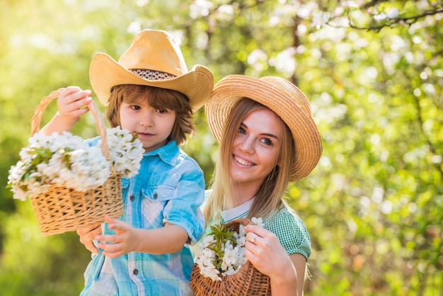 Mi dulce bebé Feliz día de la familia Madre e hijo lindo con sombreros Granja familiar Pasar tiempo juntos Encantadora familia al aire libre fondo natural Agricultores en un jardín floreciente Concepto de rancho Cultivo de flores