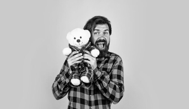 Mi mejor amigo, un tipo brutal con un regalo del día de San Valentín con amor, un hipster guapo que tiene un estado de ánimo juguetón, feliz día del padre, un hombre maduro con un oso, un hombre barbudo, sostiene un oso de peluche.