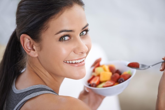 Mi merienda saludable Una mujer joven comiendo un plato de fruta picada