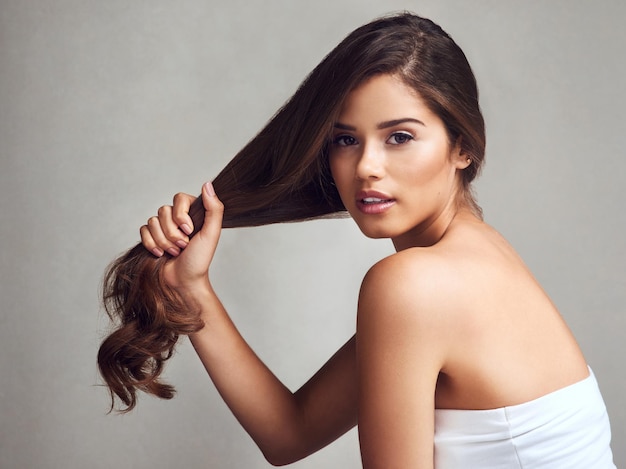 Mi régimen de cabello ha fortalecido mi cabello Foto de estudio de una mujer joven y hermosa con cabello largo y hermoso posando sobre un fondo gris