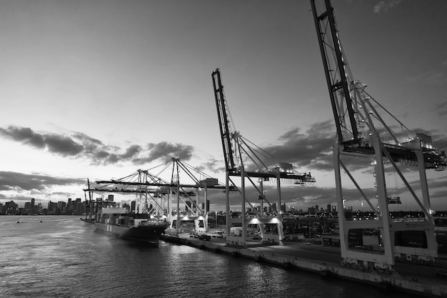 Miami EE.UU. 01 de marzo de 2016 transportista de carga y grúas en el cielo nocturno Transportista de carga en el lado del muelle Horizonte de la ciudad al atardecer Envío y envío Carga de carga