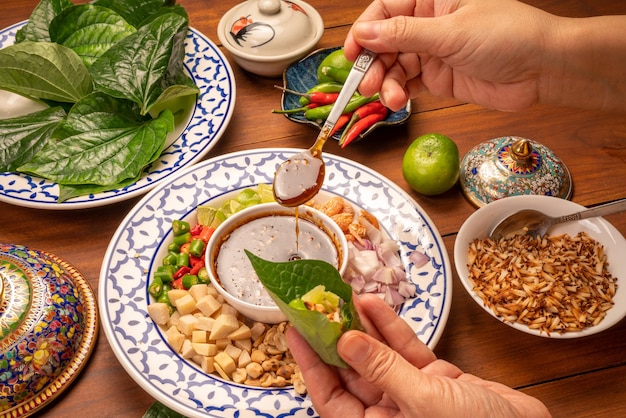 Foto miang kham ou folhas de bétele selvagem envolva ingredientes com molho doce de mergulho comida asiática aperitivo