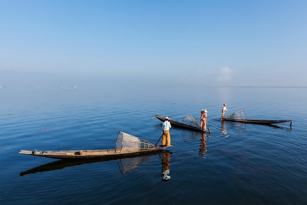 Mianmar viagem atração marco tradicional pescadores birmaneses com redes de pesca em barcos no lago Inle em Mianmar famoso por seu estilo distinto de remo de uma perna