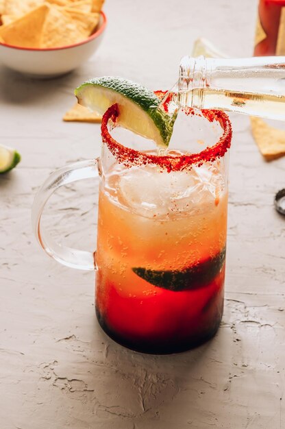 Michelada, mexikanisch inspirierter alkoholischer Bloody-Mary-Cocktail mit Bier, Limettensaft, Tomatensaft, würziger Soße und Gewürzen. Selektiver Fokus