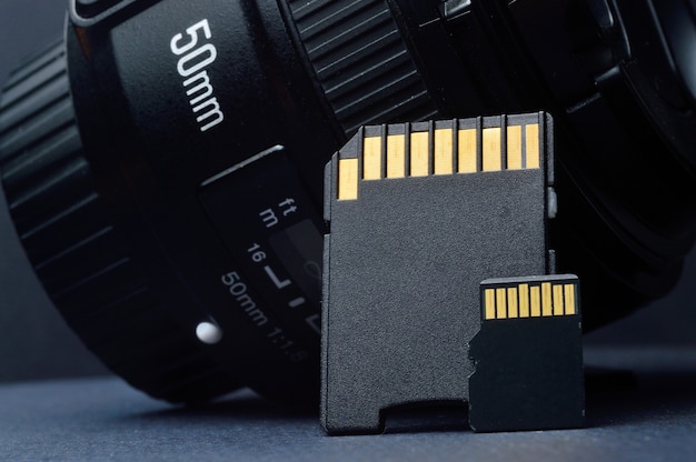 Micro-SD-Karte mit Adapter auf dem Hintergrund eines austauschbaren Objektivs für eine Digitalkamera.