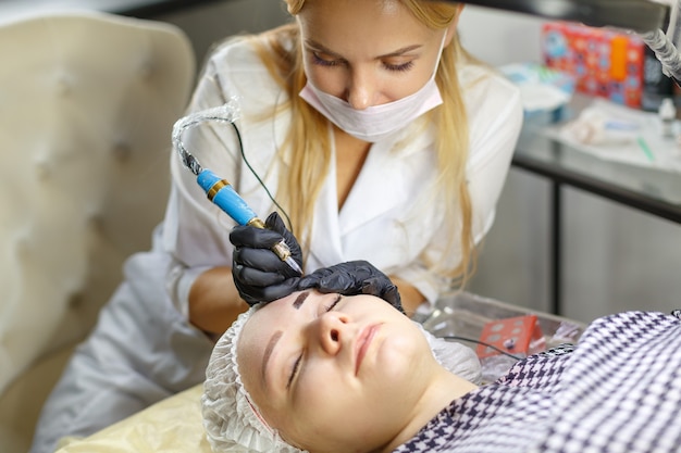 Microblading-Augenbrauen-Workflow in einem Schönheitssalon. Frau, die ihre Augenbrauen gefärbt hat. Semi-permanentes Make-up für die Augenbrauen. Konzentrieren Sie sich auf das Gesicht und die Augenbrauen des Models