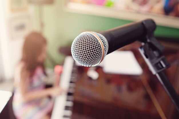 Microfone com turva menina tocando piano fundo, educação de música homeschool