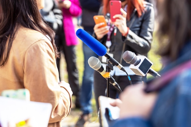 Foto microfone de conferência de imprensa em foco jornalista móvel filmando evento da mídia com um smartphone