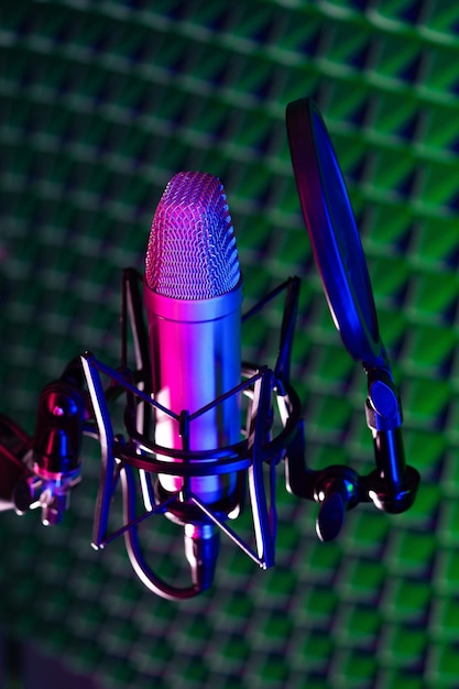 Microfone de estúdio profissional contra o fundo de painel de espuma acústica em luz de néon