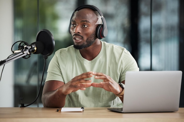 Microfone de homem negro e falando com fones de ouvido e notícias de DJ de rádio com equipamento de comunicação e áudio Podcast laptop e multimídia com apresentador masculino apresentando show e transmissão online