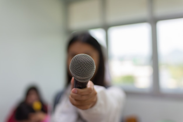 Microfone na mão de uma mulher.